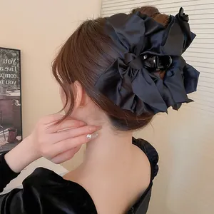 Nahaufnahme einer eleganten schwarzen Satin-Schleifen-Haarklammer in einem Dutt