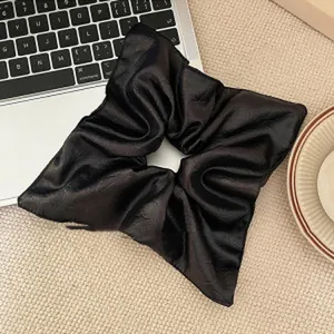 Large black pleated fabric scrunchie hair tie featuring an elegant wrinkled texture