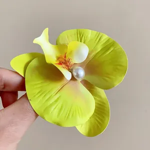 Vue détaillée d'une pince à cheveux orchidée jaune avec perle centrale
