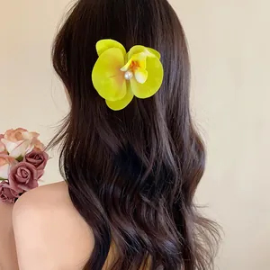 Vue arrière d'une pince à cheveux orchidée jaune avec perle sur cheveux ondulés.