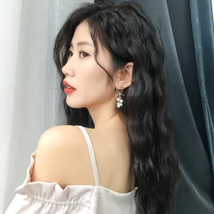 Elegant long pearl drop earrings with gold knot detail worn by a beautiful Asian model.