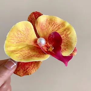 Gros plan sur une pince à cheveux orchidée jaune avec un détail de perle centrale nacrée