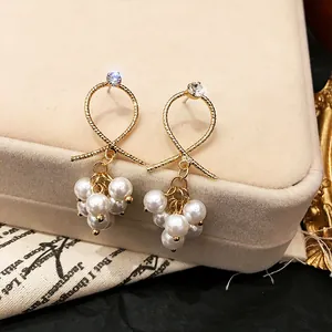Detail view of gold-tone twist loop earrings with elegant white clustered pearl drops