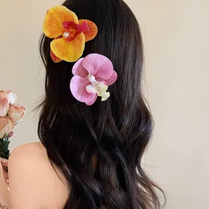 Détail de pinces à cheveux en forme d'orchidée avec perles sur cheveux sombres ondulés.