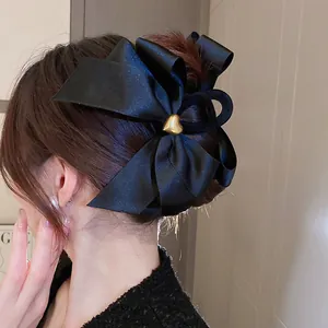 Eleganter großer schwarzer Satin-Haarclip mit goldener Herzverzierung am Modell