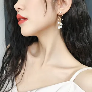 Close-up of elegant pearl drop earrings with golden bow detail on model