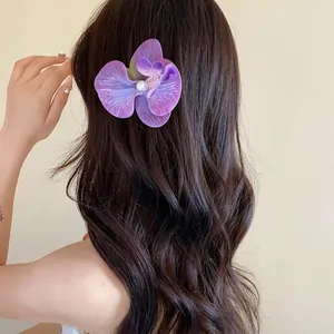 Vue détaillée d'une pince à cheveux orchidée violette avec perle sur cheveux ondulés