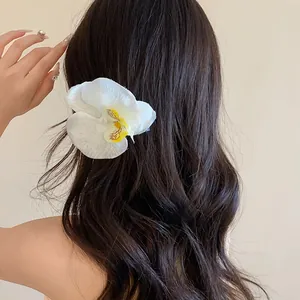 Pince à cheveux fleur orchidée blanche sur cheveux ondulés noirs pour look vacances