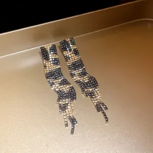 Detailed macro view of rhinestone leopard print drop earrings on golden tray