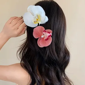 Gros plan détaillé des pinces à cheveux fleurs d'orchidées blanches et roses avec une perle