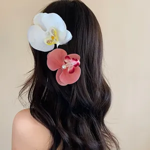 Vue détaillée de pinces à cheveux orchidée avec perles sur cheveux ondulés bruns