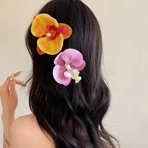 Détail de pinces à cheveux orchidées roses et jaunes avec perles sur de longs cheveux ondulés