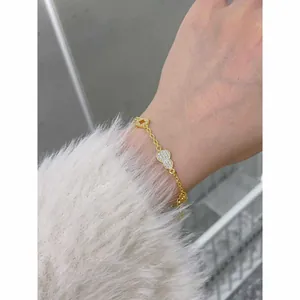 Detail view of a 24K gold-plated bracelet featuring zircon gourd and coin charms.