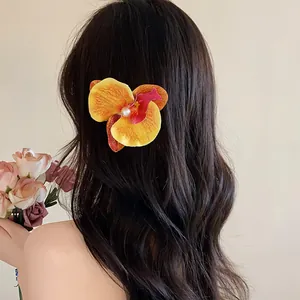 Vue détaillée d'une élégante pince à cheveux en forme d'orchidée jaune et perle