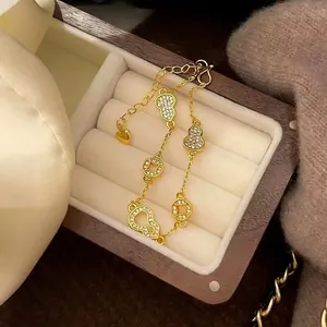 Detail view of gold-plated bracelet with zircon hulu and copper coin charms in box