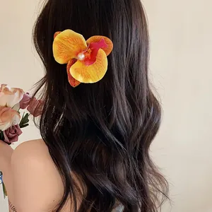 Gros plan d'une pince à cheveux orchidée Phalaenopsis avec perle sur cheveux ondulés