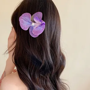 Détail d'une pince à cheveux orchidée violette avec une perle blanche au centre.