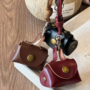 Three miniature leather coin purse necklace pendants in brown, black, and burgundy.