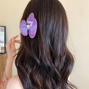 Détail d'une pince à cheveux orchidée violette avec perle sur cheveux bruns ondulés