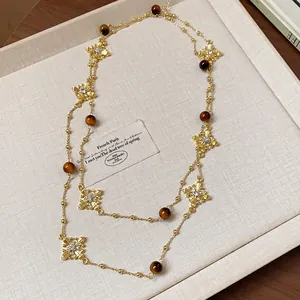 Elegant double-layer long necklace featuring tiger's eye beads and ornate gold cross pendants