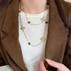 Close-up of vintage gold cross necklace with diamond accents and brown beads