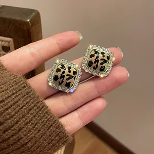Primo piano dettagliato di orecchini a lobo quadrati leopardati con un alone di strass brillanti