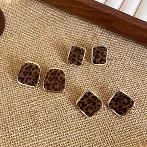 Detail view of flocked leopard print stud earrings on burlap background