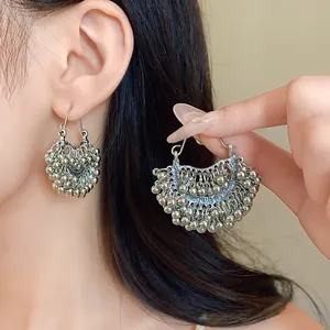 Detailed macro view of ethnic style silver crescent earrings featuring beaded tassel fringe