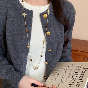 Detail view of a vintage gold cross necklace with tiger eye beads worn on a model.