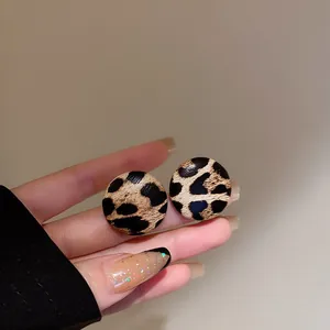 Primo piano di orecchini a lobo circolari leopardati con eleganti motivi marroni e neri.
