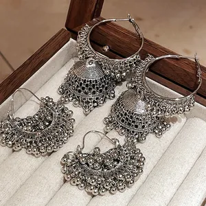 Detailed view of vintage silver ethnic Jhumka earrings with bead tassels in a wooden jewelry box.