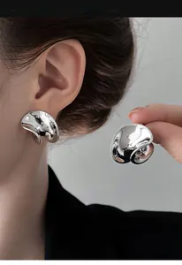 Primo piano di orecchini a perno in metallo argento con design irregolare lucido
