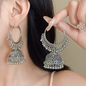 Detailed view of silver ethnic Jhumka style earrings with bead tassels on a model