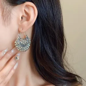 Detail view of ethnic silver beaded tassel earrings elegantly worn by an Asian model