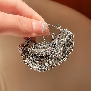 Close-up of ethnic silver beaded tassel hoop earrings with intricate geometric design