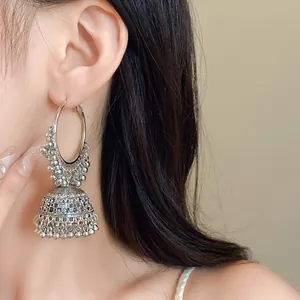 Detailed view of ethnic style silver hoop earrings with bead tassel on female model