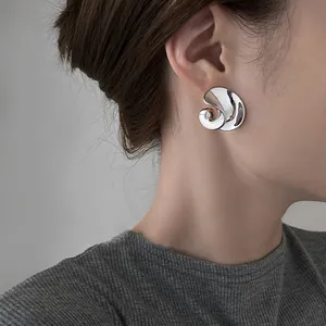 Dettaglio dell'orecchino a lobo a spirale in metallo argento indossato da un modello.