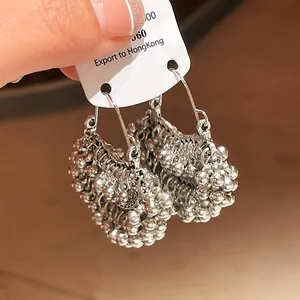 Close-up view of ethnic style silver beaded tassel hoop earrings for women in hand
