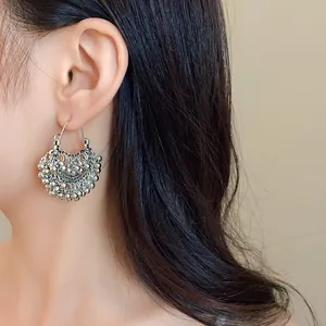 Close-up of ethnic silver beaded tassel earrings worn by a model for a stylish look.
