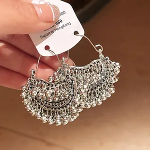 Detail view of silver ethnic hoop earrings with dangling metal bead tassels