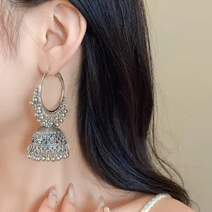 Close-up of ethnic silver Jhumka earrings with intricate bead tassels on model