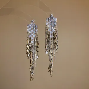 Detailed view of elegant tassel earrings with sparkling zircons and golden leaf chains.