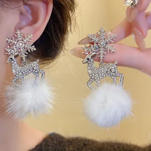 Detail of reindeer and snowflake drop earrings with sparkling rhinestones and soft white fur balls.