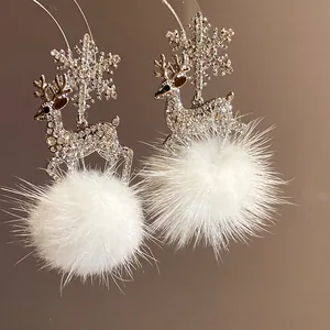 Close-up detail of Christmas reindeer earrings with snowflake and white fur ball