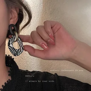 Pendientes retro de acrílico con patrón de cebra y eslabones dorados en modelo