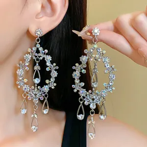 Detailed view of oversized silver needle earrings with shimmering iridescent AB rhinestones