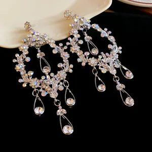 Detail shot of silver tassel earrings featuring hollow teardrop designs and rhinestones.