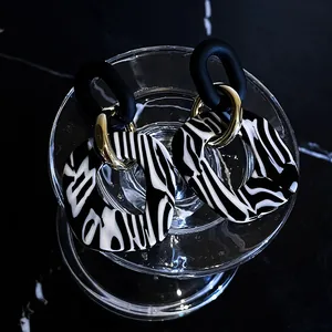 Vista detallada macro de pendientes de acrílico con patrón de cebra y elegantes tonos oro