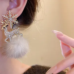 Close-up of Christmas snowflake reindeer earrings with rhinestones and fur pom-poms