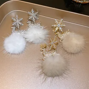 Detailed view of rhinestone snowflake and reindeer earrings with fluffy fur balls